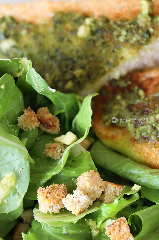 鸡肉凯撒沙拉的全帧图像脆绿色长叶莴苣叶，面包丁与帕玛森奶酪切片，大蒜面包片涂上绿色香蒜酱，高架视图，重点在前景