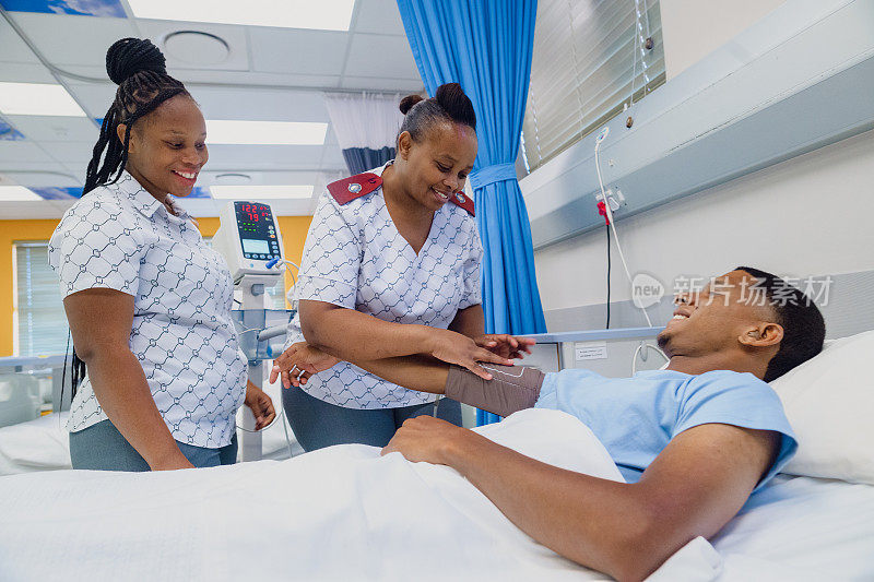 在繁忙的医院病房里，友善的女护士在病床上给戴着助听器的年轻男性测血压