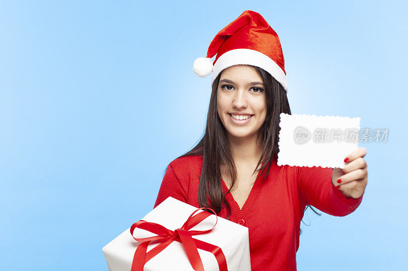 快乐的女人戴着圣诞帽拿着圣诞礼物，展示着贺卡。
