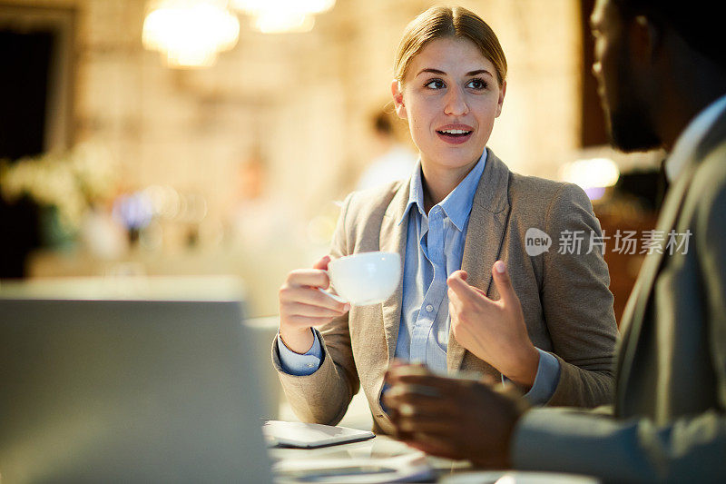 积极迷人的商务女士在夹克喝咖啡与同事和分享她的想法和计划