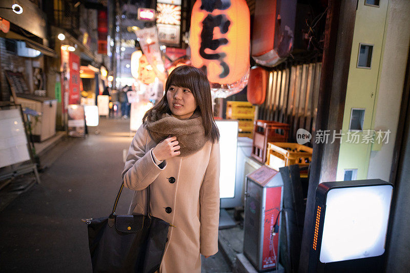 一名年轻女子第一次走在日本居酒屋狭窄的街道上