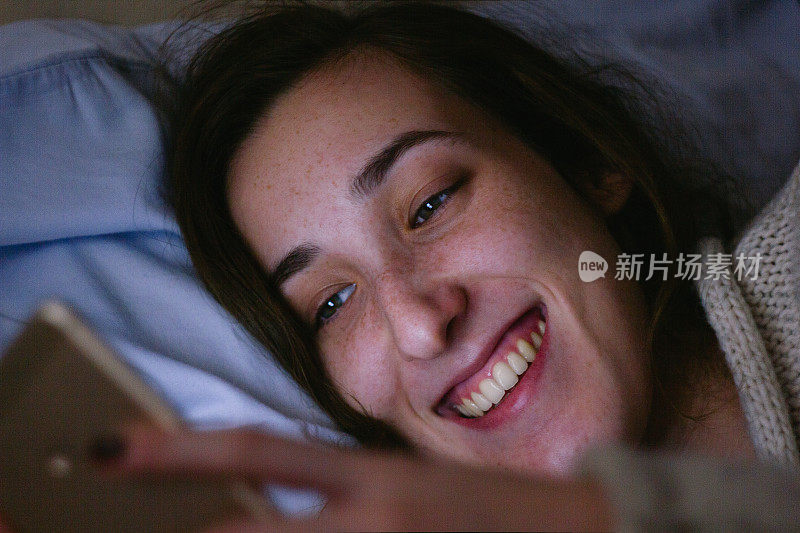 年轻女子在床上使用手机
