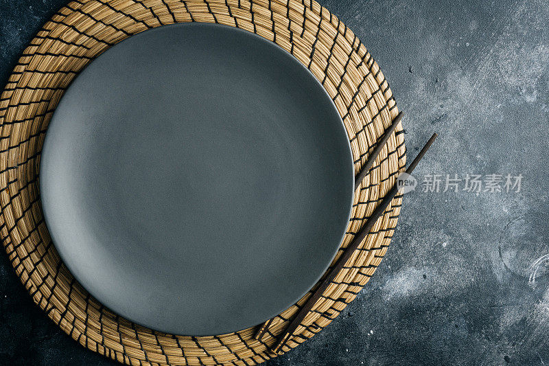 灰色的空盘子(陶瓷)与中国筷子在灰色的石头背景。中国菜。灰色的极简主义的概念。副本的空间。