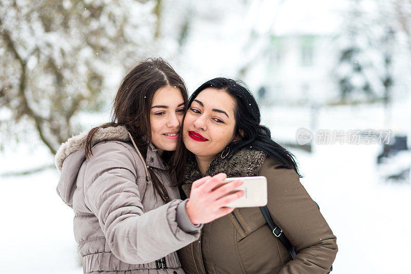 快乐的母女在雪中自拍