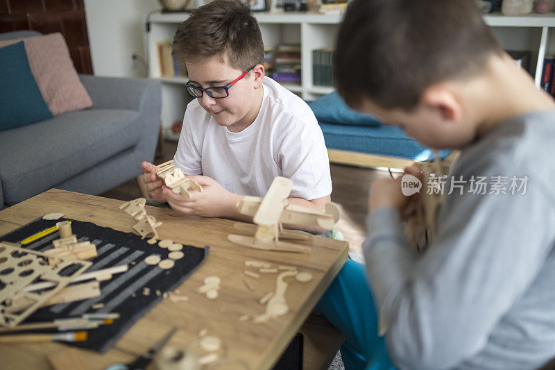 兄弟们正在为学校项目制作木制模型飞机