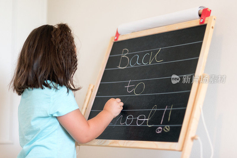 可爱的小女生在黑板上写字带着文字回学校。