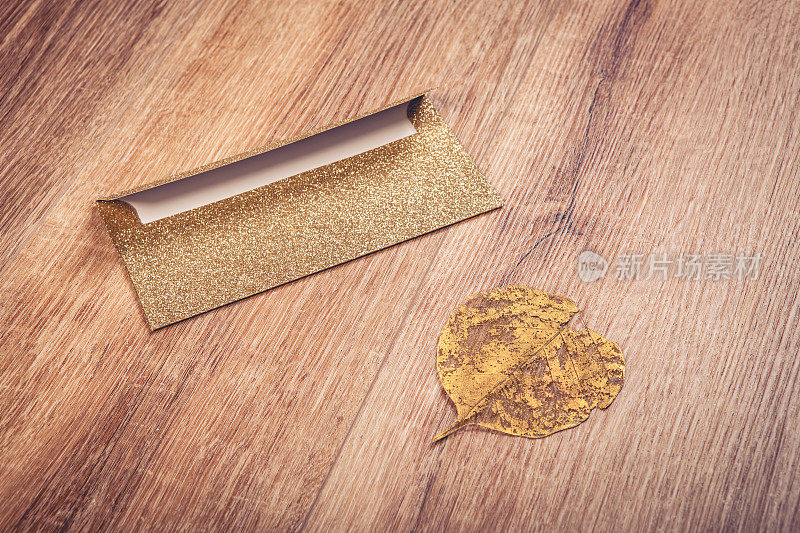 金色的信封和树叶铺在木地板上