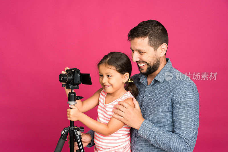 父亲向他可爱的小女儿展示如何使用相机