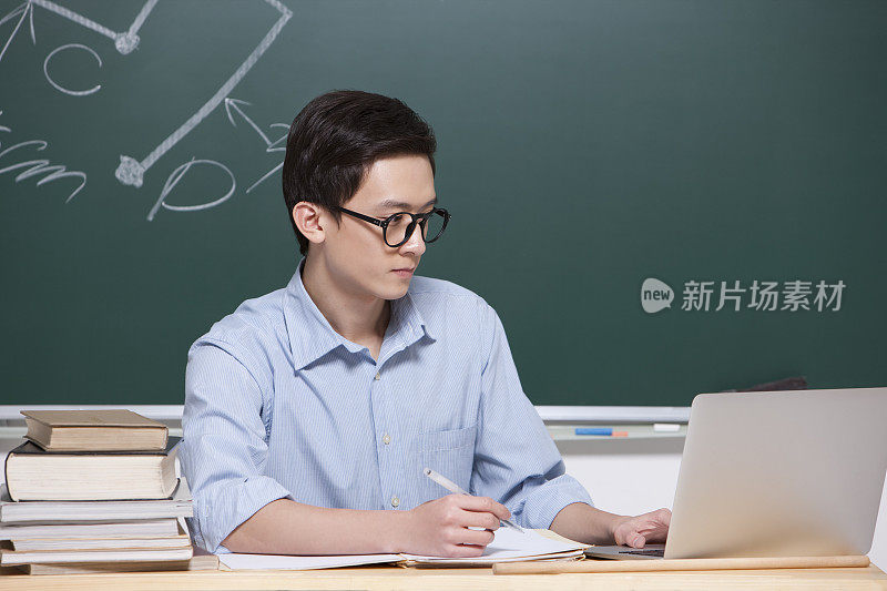 男老师在教室使用笔记本电脑