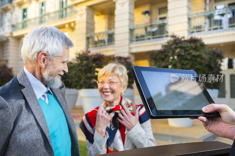 酒店接待员用平板电脑迎接老夫妇