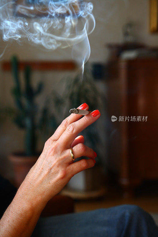 女人手里拿着一支点燃的香烟