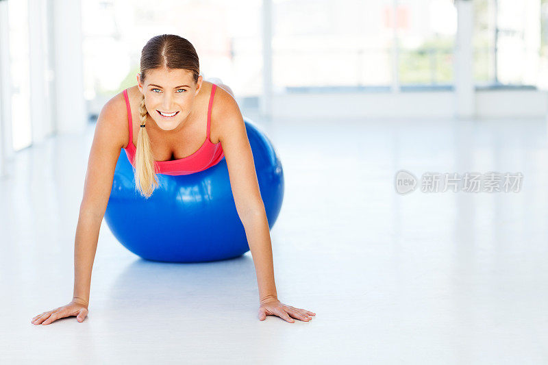 在健身房用普拉提球做俯卧撑的女人