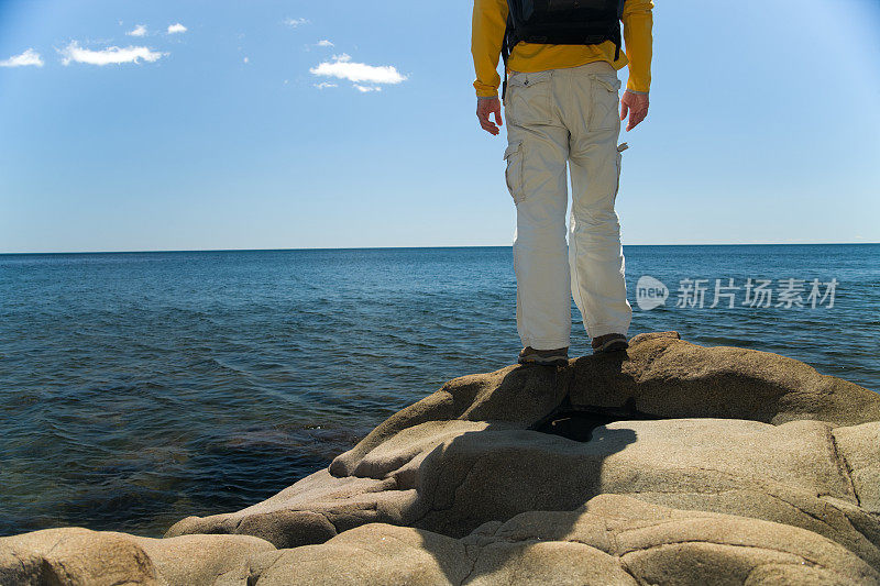 一个徒步旅行者站在斯皮尔兹湖的岩石海岸线上。