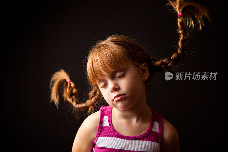 小女孩睡觉与向上的辫子在黑色的背景