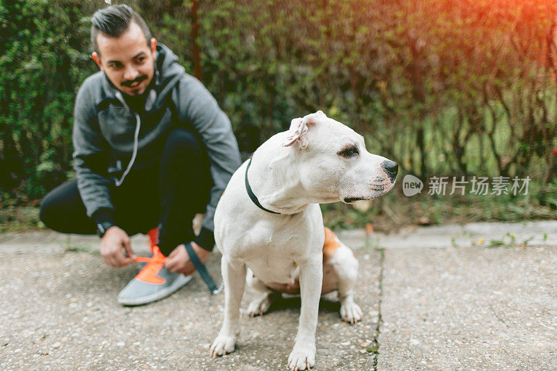 男人在户外给他的狗系鞋带。