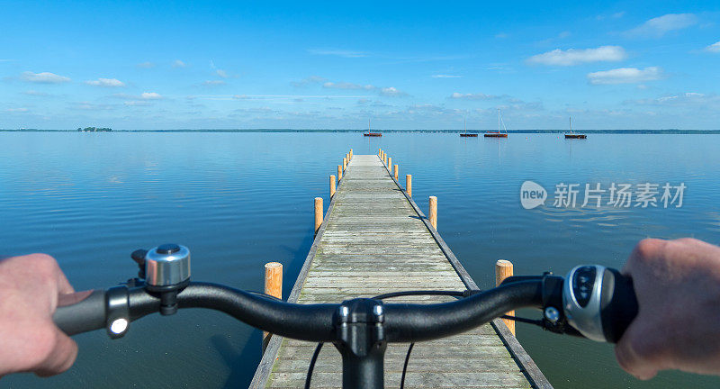 在湖边的防波堤前，骑自行车的人把手放在车把上
