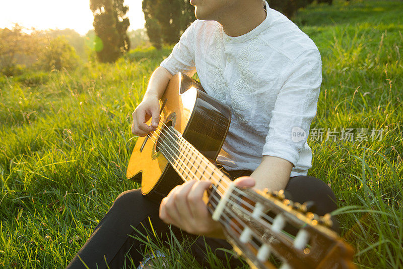 一个人坐在草地上弹吉他