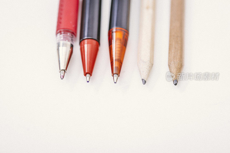 许多钢笔和铅笔在白色背景上画得更近了