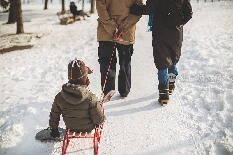 父母用雪橇拉着他们的儿子