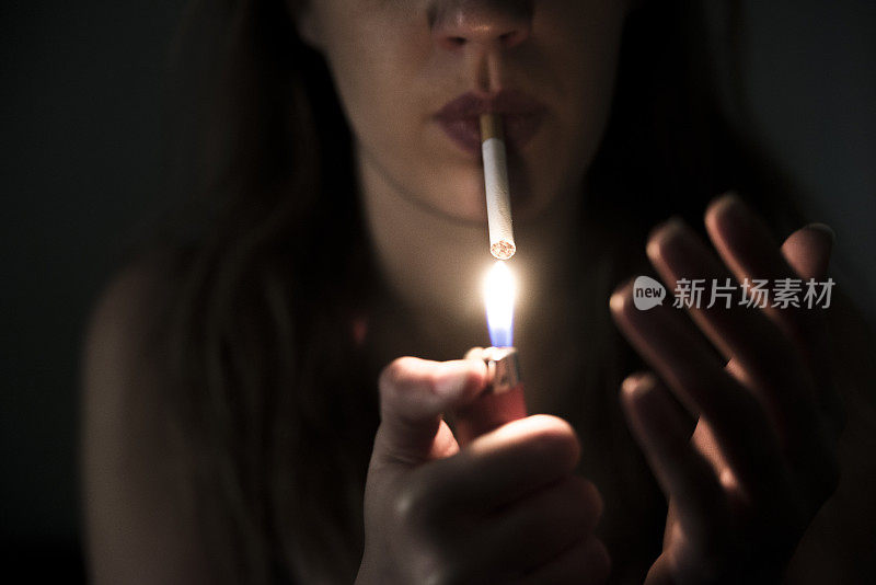 近距离的香烟在不健康的女孩手中点燃