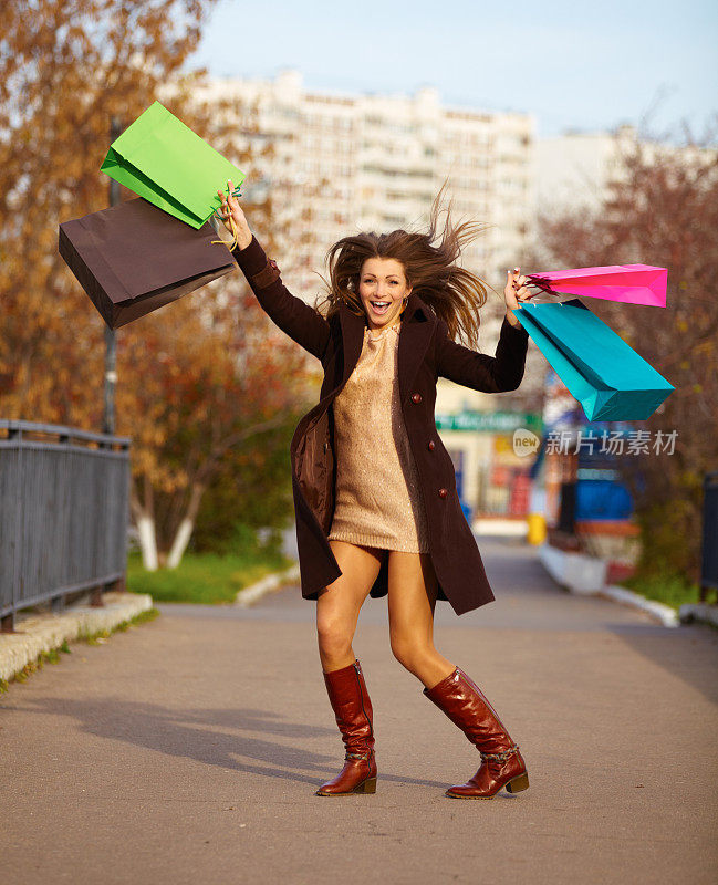 快乐的女人拿着购物袋，蹦蹦跳跳
