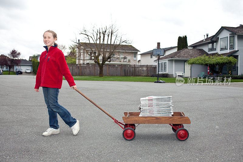 一个年轻女孩拉着一辆马车在她的社区送报纸。