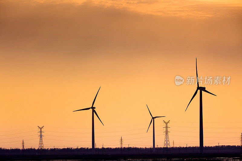 日落时的风力涡轮机和电力塔