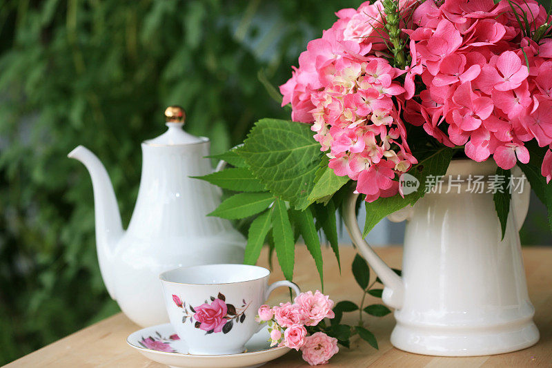 花瓶里有粉红色的绣球花，还有咖啡壶和杯子