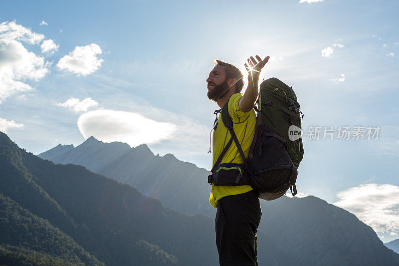 日出时分，一名男子站在山顶，双臂张开