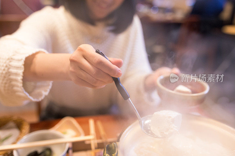 年轻女子从火锅里捡豆腐