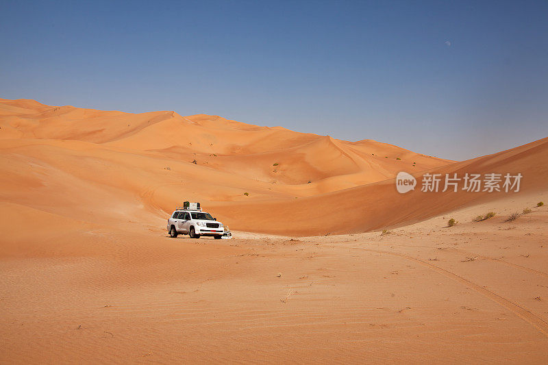 汽车在沙丘之间的沙漠中行驶