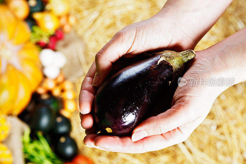在农贸市场，人们手里拿着闪亮的紫色茄子