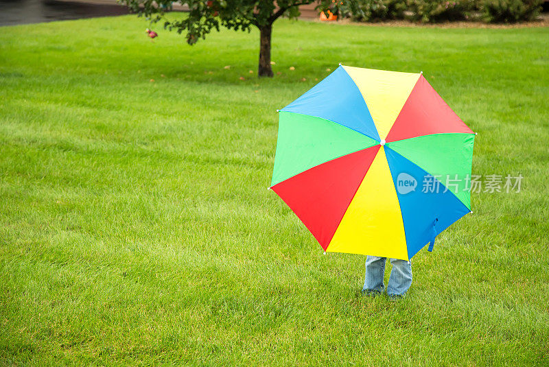 站在彩色雨伞后面的孩子