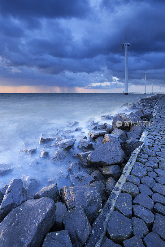 荷兰堤上的风力涡轮机上乌云密布
