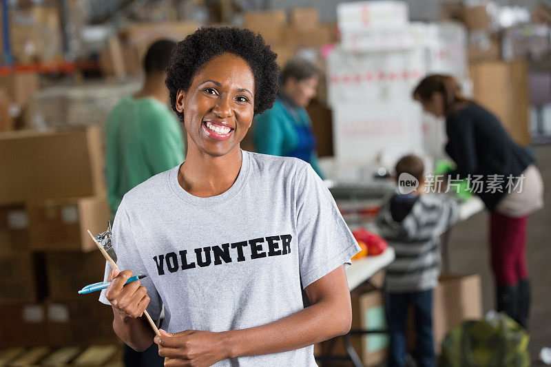 热心的志愿者在繁忙的社区食品银行拿着剪贴板