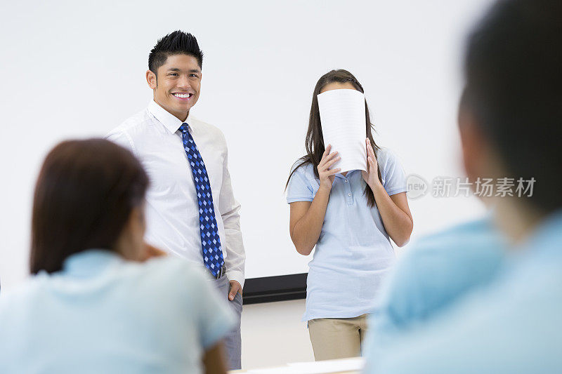 尴尬的学生在教室里做报告时遮住脸