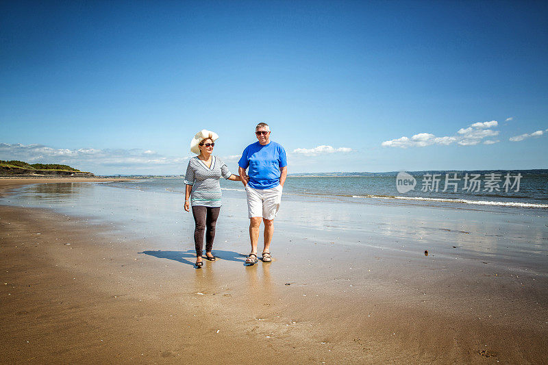 一对成熟的微笑情侣在海滩上散步