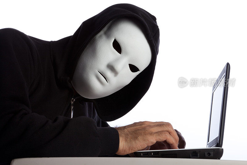 戴着面罩和头巾的黑客正在使用电脑
