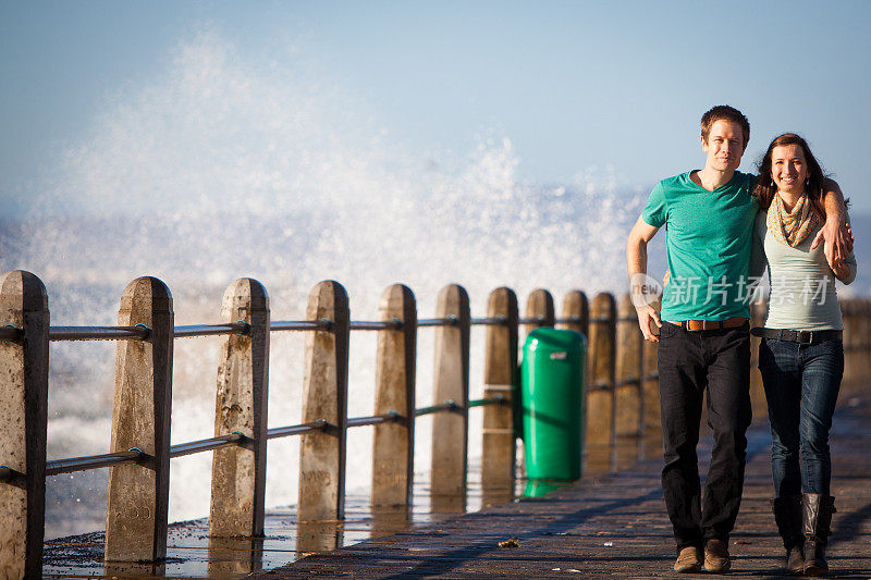 在海浪溅起水花的背景下散步