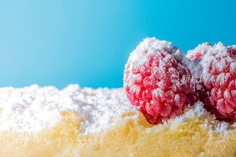 甜烤华夫饼与树莓和糖粉近距离微距在一个蓝色的背景