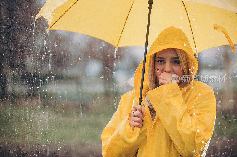 穿着黄色衣服的女人站在雨中