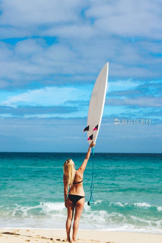 冲浪女孩拿着冲浪板在海滩上