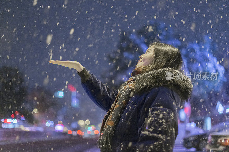 一个美丽的女人，在夜晚仰望着雪花