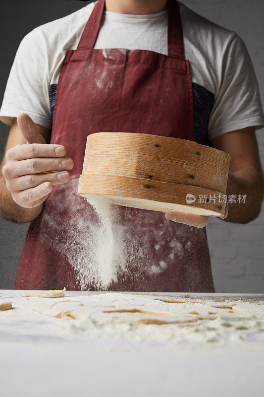 厨师用筛子筛面粉的裁剪图像