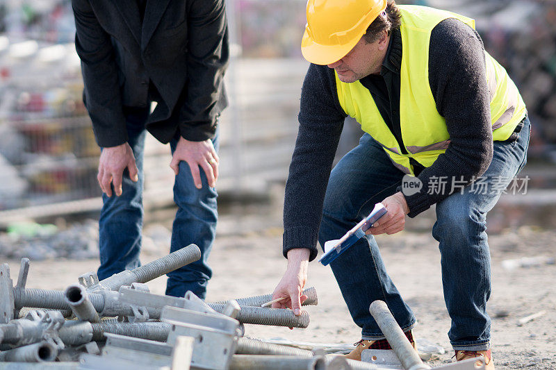 蹲伏土木工程师检查建筑工地的金属管