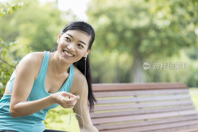 快乐的女人在运动间歇取出耳塞