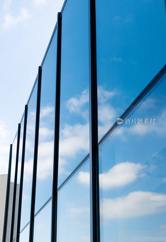 云朵映在现代建筑的玻璃窗上