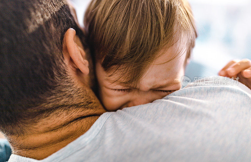 小男孩在父亲的怀抱里哭泣的特写。