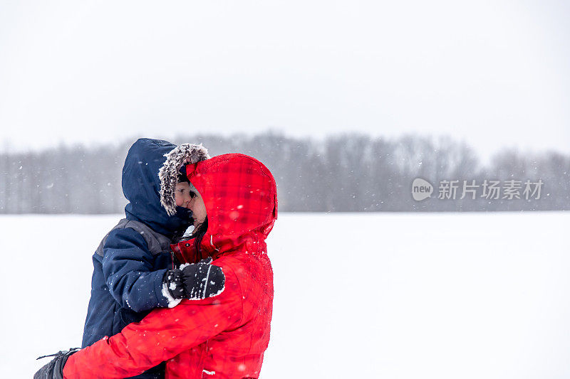 母亲和儿子在暴风雪期间户外玩耍