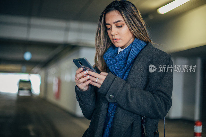 一名年轻女子在地下车库使用手机